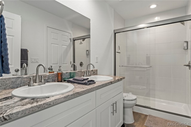 bathroom featuring hardwood / wood-style floors, vanity, toilet, and an enclosed shower