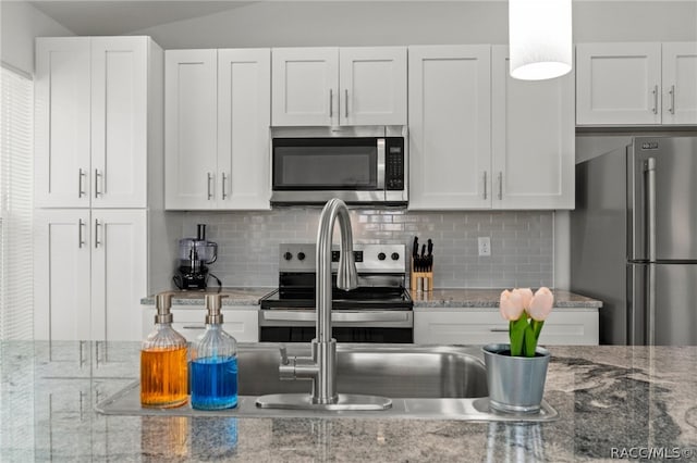 kitchen featuring light stone countertops, appliances with stainless steel finishes, and white cabinetry