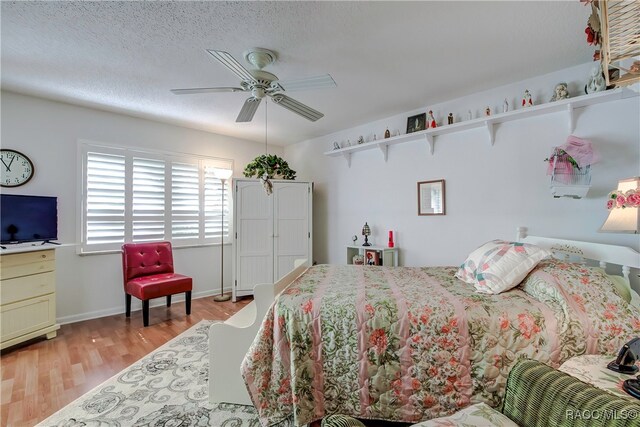 bedroom with a textured ceiling, light hardwood / wood-style flooring, and ceiling fan