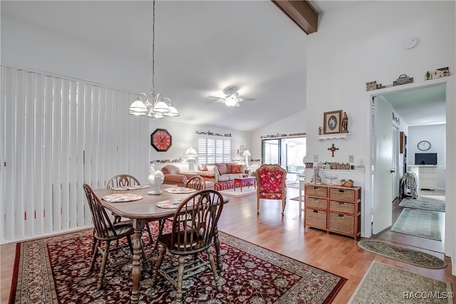 dining area featuring beam ceiling, high vaulted ceiling, ceiling fan with notable chandelier, and light wood-type flooring