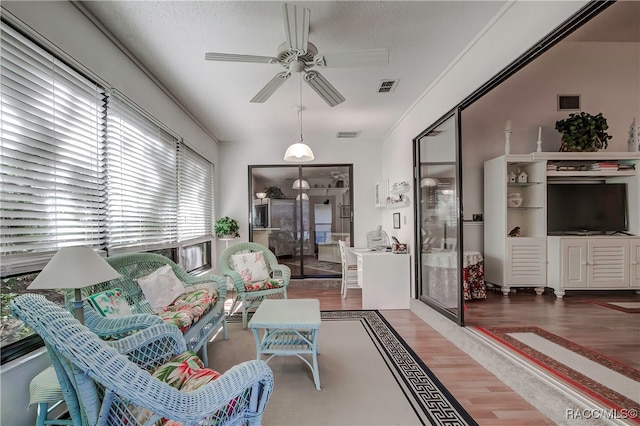 living room with hardwood / wood-style flooring, ceiling fan, and a textured ceiling