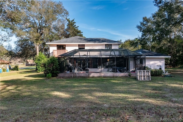 rear view of property featuring a lanai and a lawn