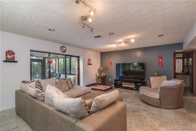 living room with french doors, a textured ceiling, and track lighting