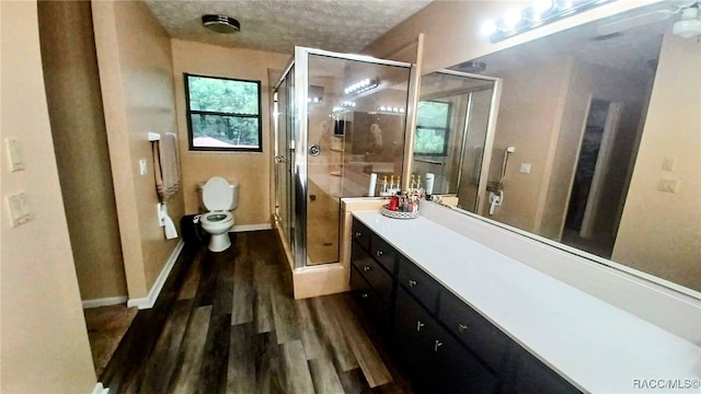 bathroom with an enclosed shower, a textured ceiling, vanity, hardwood / wood-style flooring, and toilet