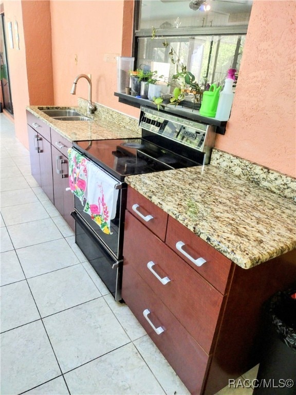 kitchen featuring light stone counters, light tile patterned floors, sink, and black range with electric cooktop