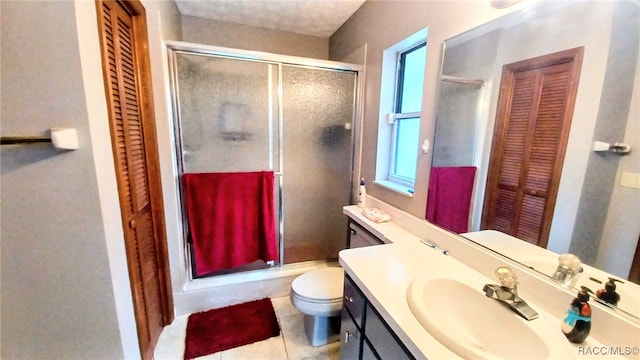 bathroom featuring tile patterned flooring, vanity, a shower with shower door, and toilet