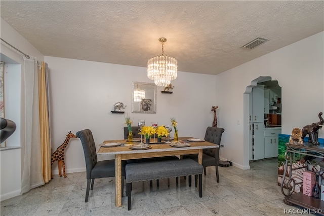 dining area with a textured ceiling and a notable chandelier