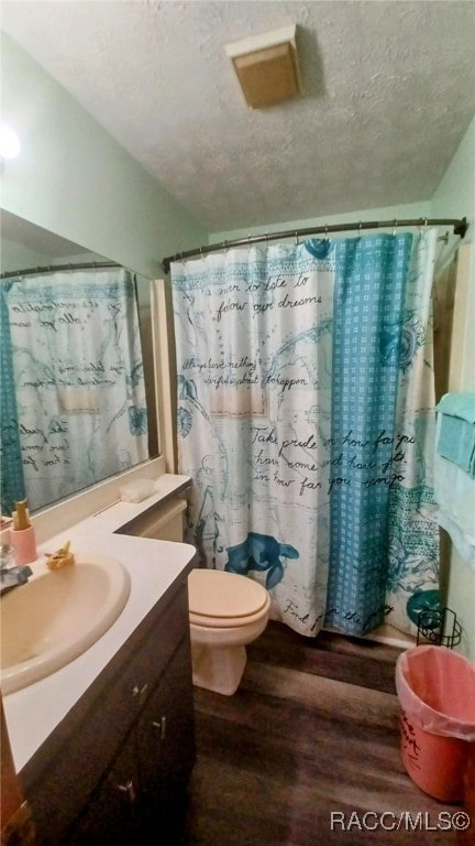 bathroom with vanity, a textured ceiling, wood-type flooring, toilet, and curtained shower