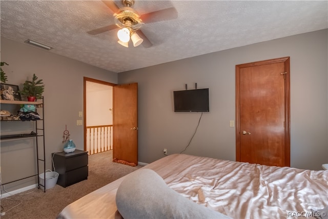 carpeted bedroom with ceiling fan and a textured ceiling