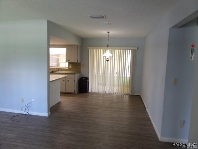 kitchen featuring white cabinetry, hanging light fixtures, dark hardwood / wood-style floors, and tasteful backsplash