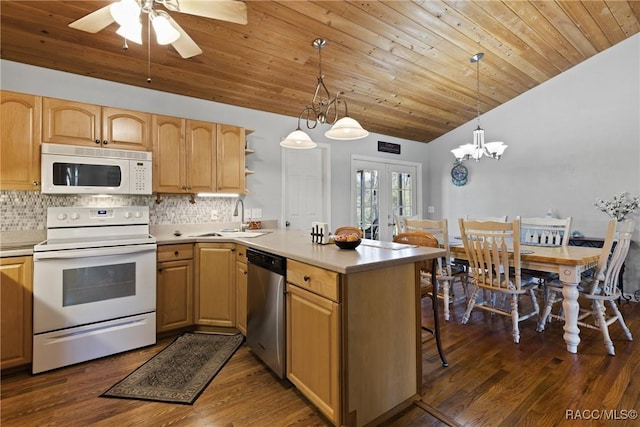 kitchen featuring backsplash, white appliances, a peninsula, and a sink