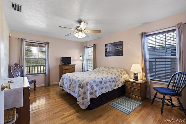 bedroom featuring visible vents, baseboards, light wood-style floors, and ceiling fan