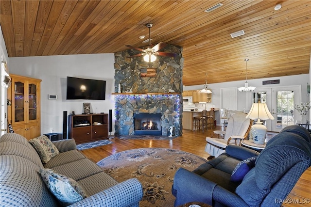 living area featuring wooden ceiling, wood finished floors, a fireplace, and ceiling fan with notable chandelier