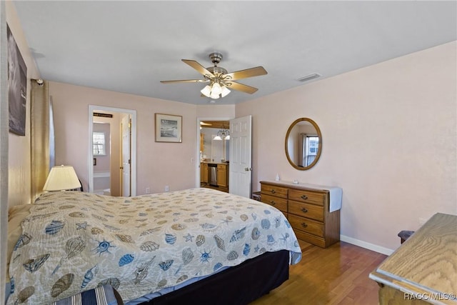 bedroom with a ceiling fan, wood finished floors, visible vents, and baseboards