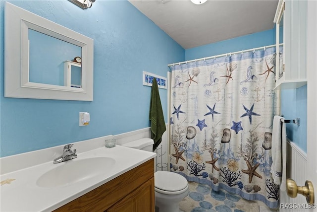 bathroom with vanity, curtained shower, toilet, and wainscoting