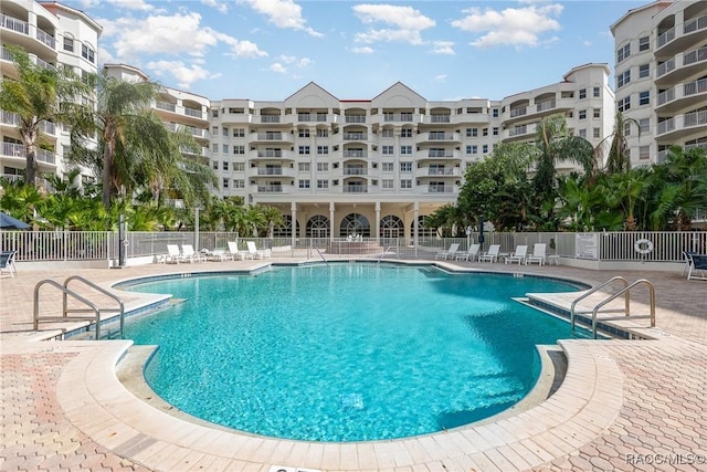 community pool with a patio area and fence