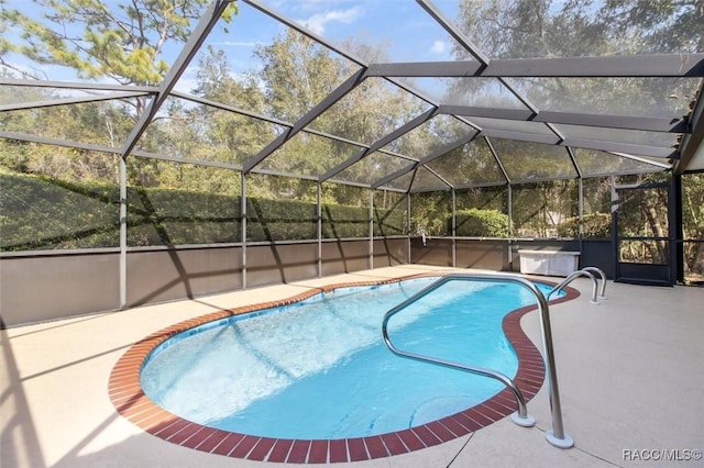 view of pool with a hot tub, a patio, and glass enclosure