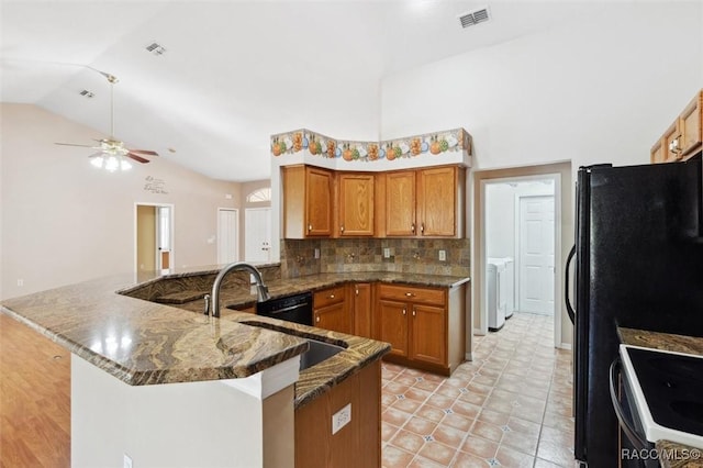 kitchen with white electric stove, sink, backsplash, dark stone counters, and kitchen peninsula