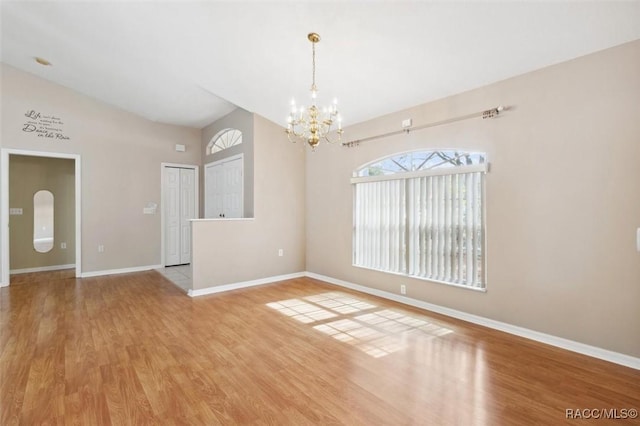 unfurnished room featuring a notable chandelier, lofted ceiling, and light wood-type flooring