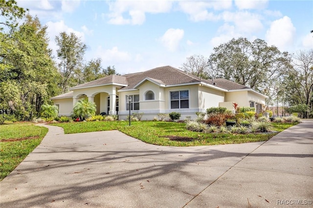 view of front of property featuring roof with shingles, a front yard, and stucco siding