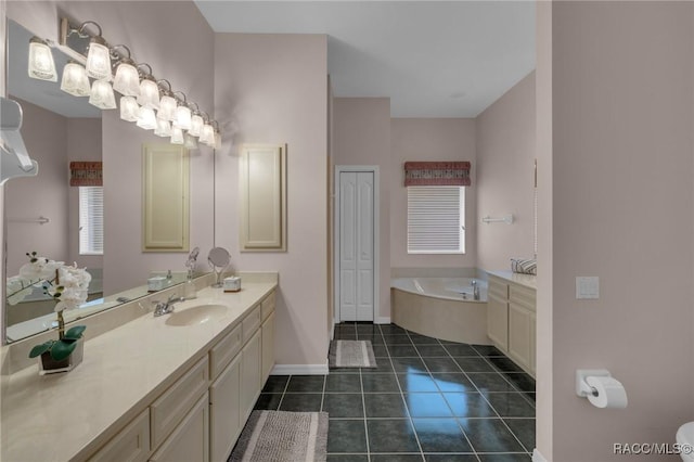 bathroom with a garden tub, a closet, vanity, baseboards, and tile patterned floors