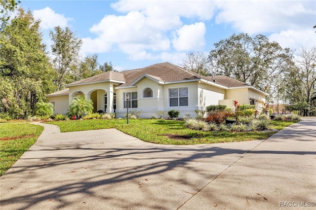 mediterranean / spanish house featuring roof with shingles, a front lawn, concrete driveway, and stucco siding