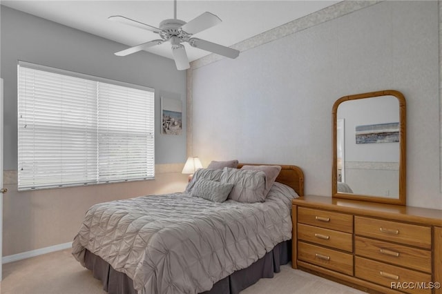 bedroom featuring light carpet, a ceiling fan, and baseboards