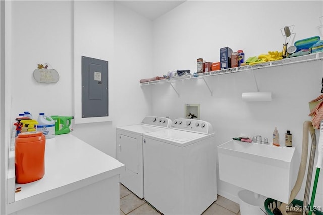 laundry room featuring laundry area, light tile patterned floors, electric panel, washing machine and clothes dryer, and a sink