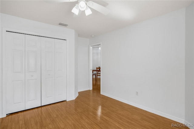 unfurnished bedroom with wood finished floors, visible vents, baseboards, ceiling fan, and a closet