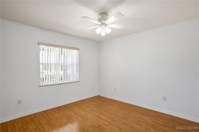 empty room featuring ceiling fan, baseboards, and wood finished floors