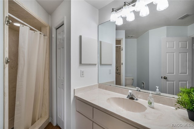 bathroom featuring visible vents, toilet, vanity, and a shower with curtain