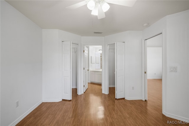 unfurnished bedroom featuring ceiling fan, visible vents, baseboards, and wood finished floors