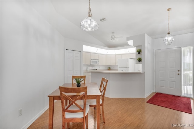 dining area featuring vaulted ceiling, light wood-style floors, visible vents, and baseboards