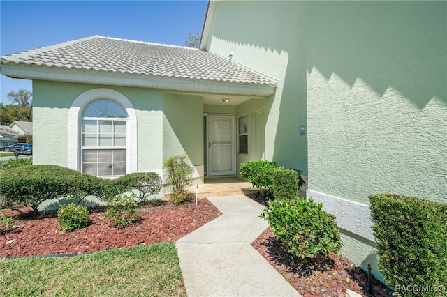 entrance to property with stucco siding and a tiled roof