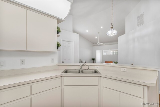 kitchen with light countertops, a peninsula, visible vents, and a sink