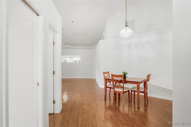 dining space featuring baseboards, an inviting chandelier, and wood finished floors