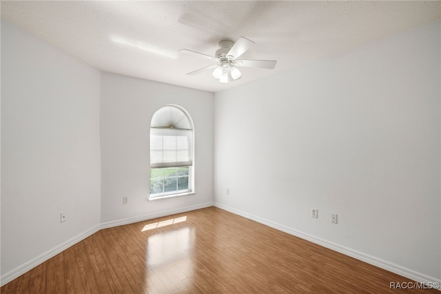 empty room featuring ceiling fan, baseboards, and wood finished floors