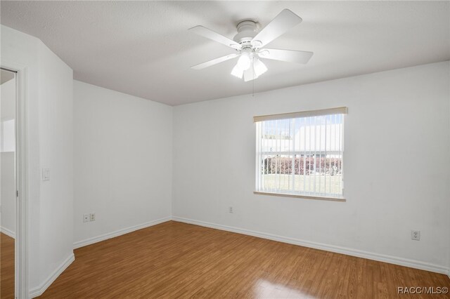 spare room featuring a ceiling fan, baseboards, and wood finished floors