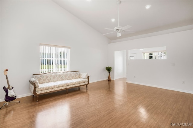 living area with a ceiling fan, wood finished floors, baseboards, and high vaulted ceiling