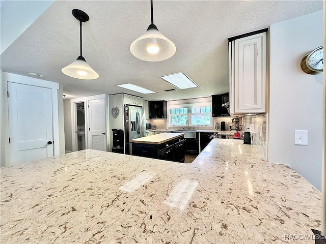 kitchen featuring tasteful backsplash, decorative light fixtures, a textured ceiling, and black appliances