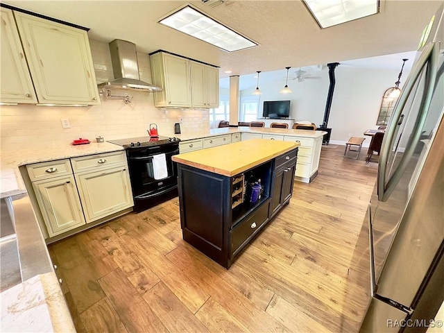 kitchen featuring decorative light fixtures, a center island, kitchen peninsula, black electric range, and wall chimney range hood