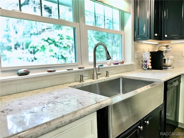 kitchen with light stone counters, dishwasher, sink, and decorative backsplash