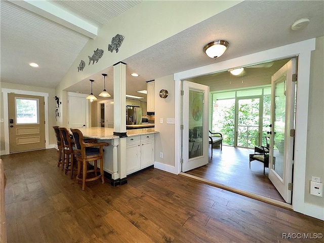 kitchen with white cabinetry, light stone counters, pendant lighting, and dark hardwood / wood-style floors