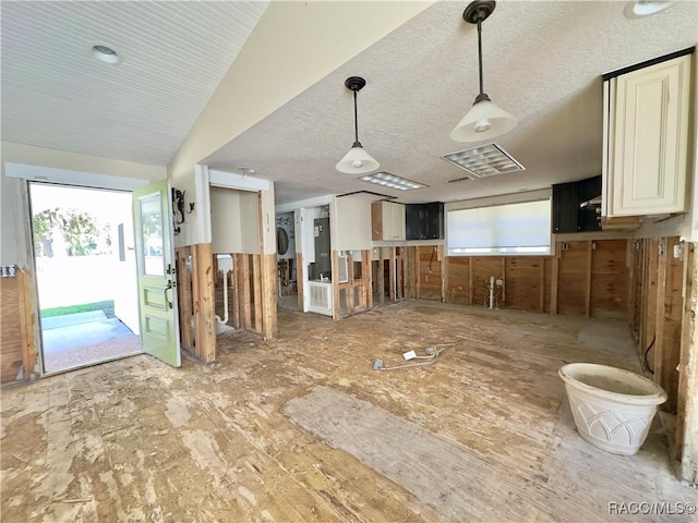 kitchen with stacked washing maching and dryer, lofted ceiling, a textured ceiling, and decorative light fixtures