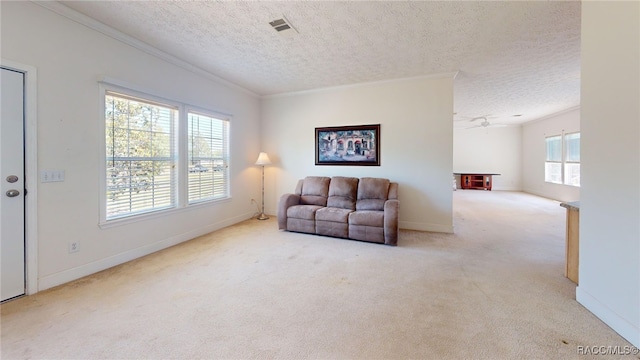 living room with a textured ceiling, baseboards, visible vents, light colored carpet, and crown molding