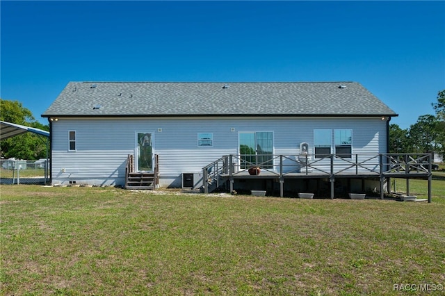 back of property featuring fence, a lawn, a shingled roof, and a deck
