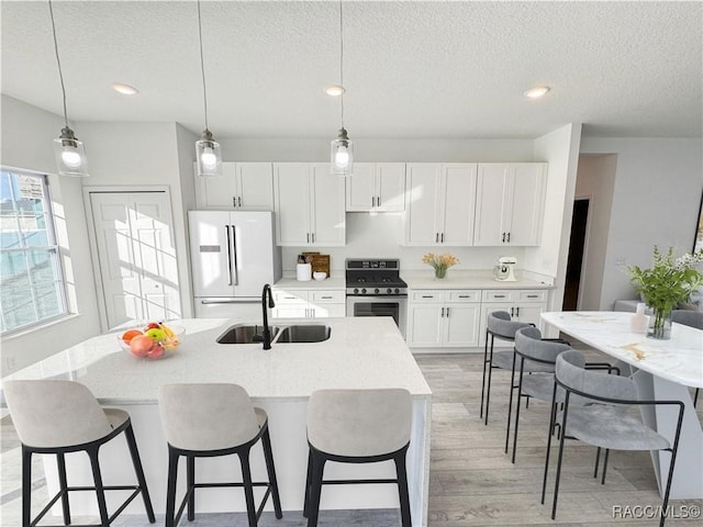 572 W Bluster Pl, Citrus Springs, FL 34434 - kitchen featuring gas stove, freestanding refrigerator, light wood-style flooring, a textured ceiling, and white cabinetry