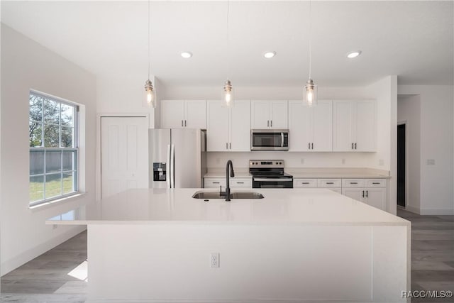 572 W Bluster Pl, Citrus Springs, FL 34434 - kitchen featuring appliances with stainless steel finishes, light wood finished floors, white cabinetry, a kitchen island with sink, and light countertops