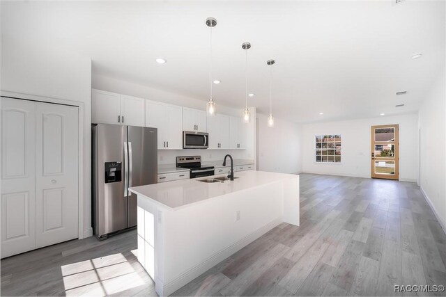 572 W Bluster Pl, Citrus Springs, FL 34434 - kitchen featuring appliances with stainless steel finishes, white cabinets, a center island with sink, light wood finished floors, and recessed lighting