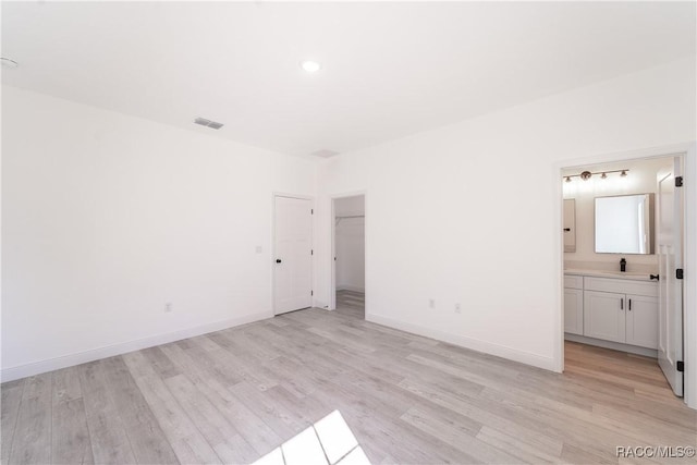 572 W Bluster Pl, Citrus Springs, FL 34434 - unfurnished bedroom featuring light wood-style floors, connected bathroom, and recessed lighting